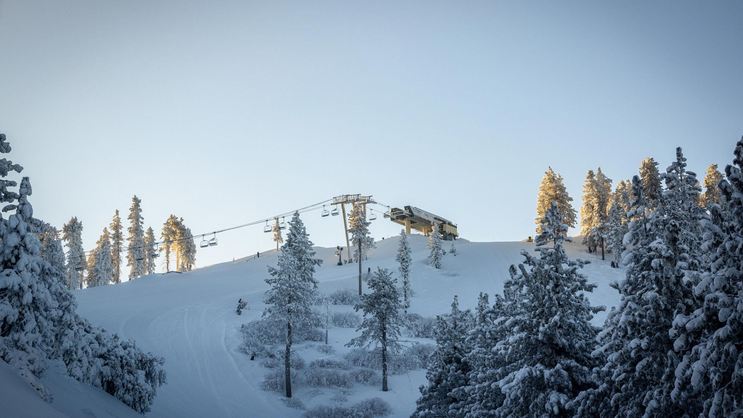 View of a snowy mountain and the top of a chairlift.