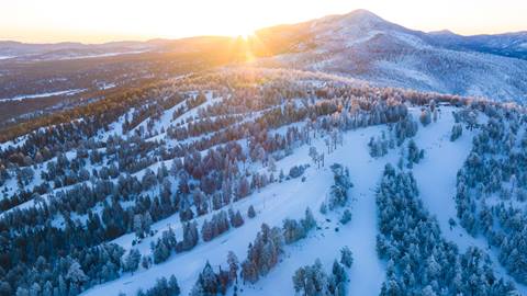 Drone image during sunrise of Snow Summit and the winter wonderland of trees and ski trails.