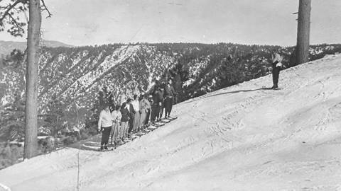 A group of skiers, on a cloudless winter day, posing for a photo on a ski trail at Snow Valley.