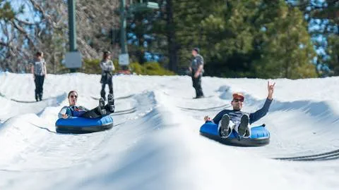 Two adults gliding down two tube lanes at Snow Valley's Coyote Creek Tube Park