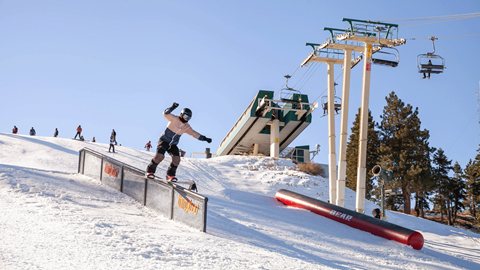 Snowbaorder doing a trick off a rail right off Chair 9 at Bear Mountain