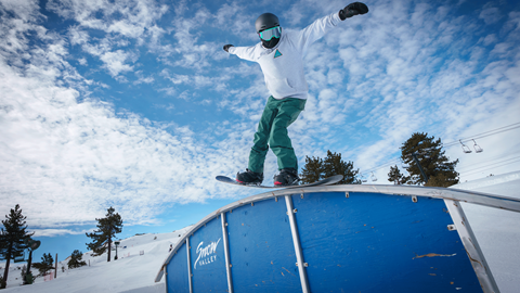 Snowboarder at Snow Valley grinding on a blue rail feature