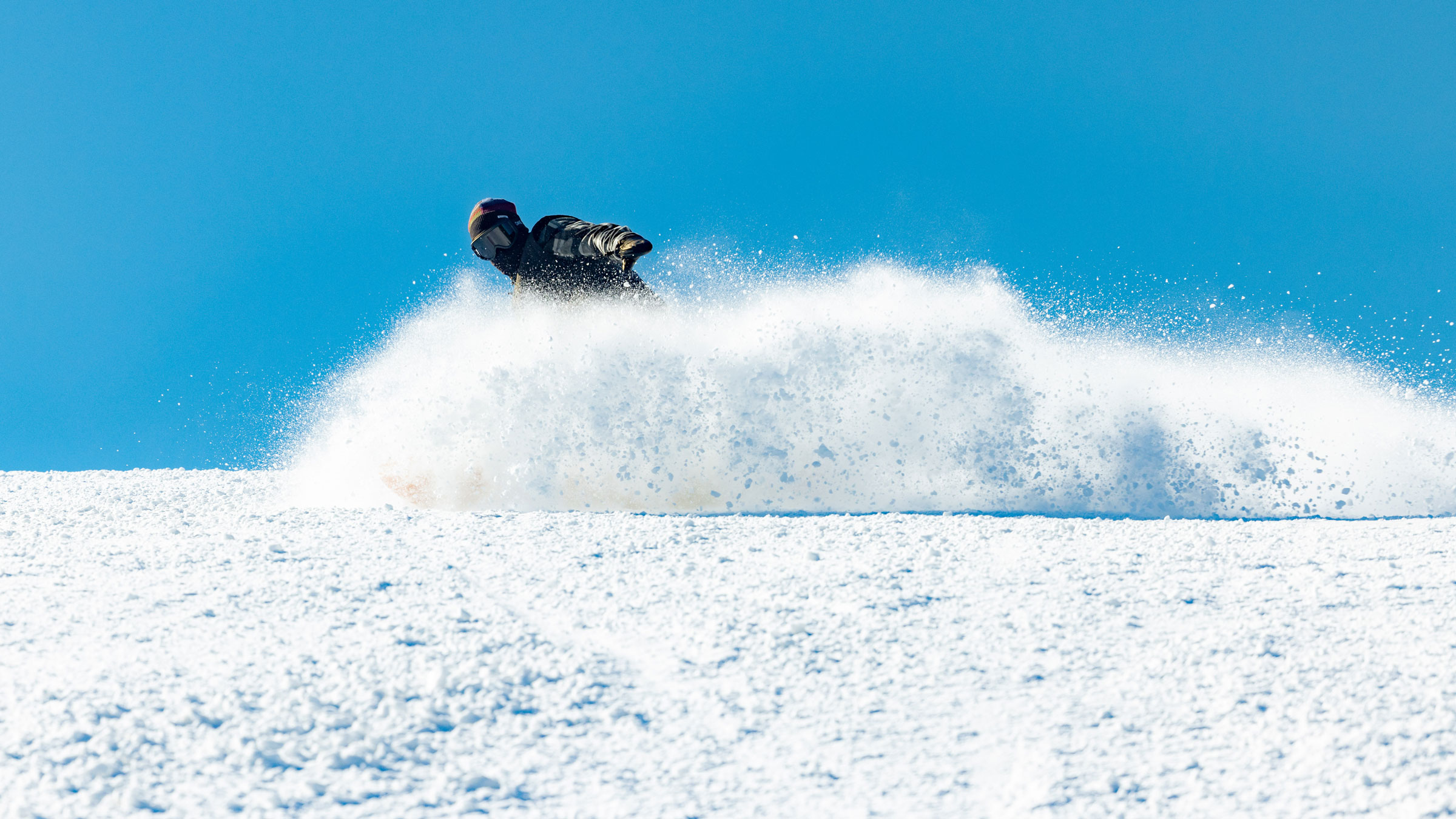 Snowboarder in fresh powder with sunny skies