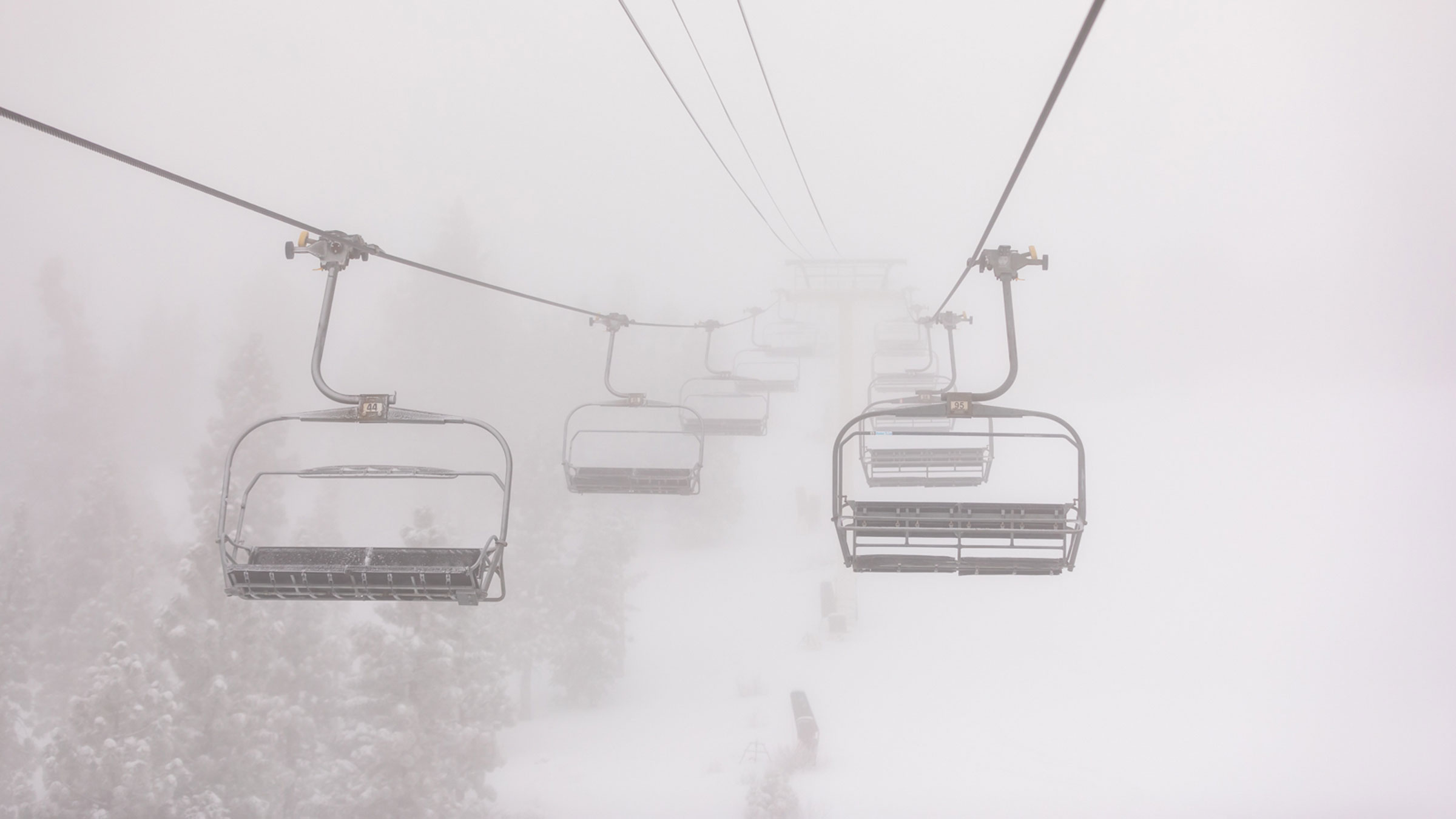 A view from the chairlift looking ahead during a low visibility winter storm day at one of the Big Bear Mountain Resort resorts.