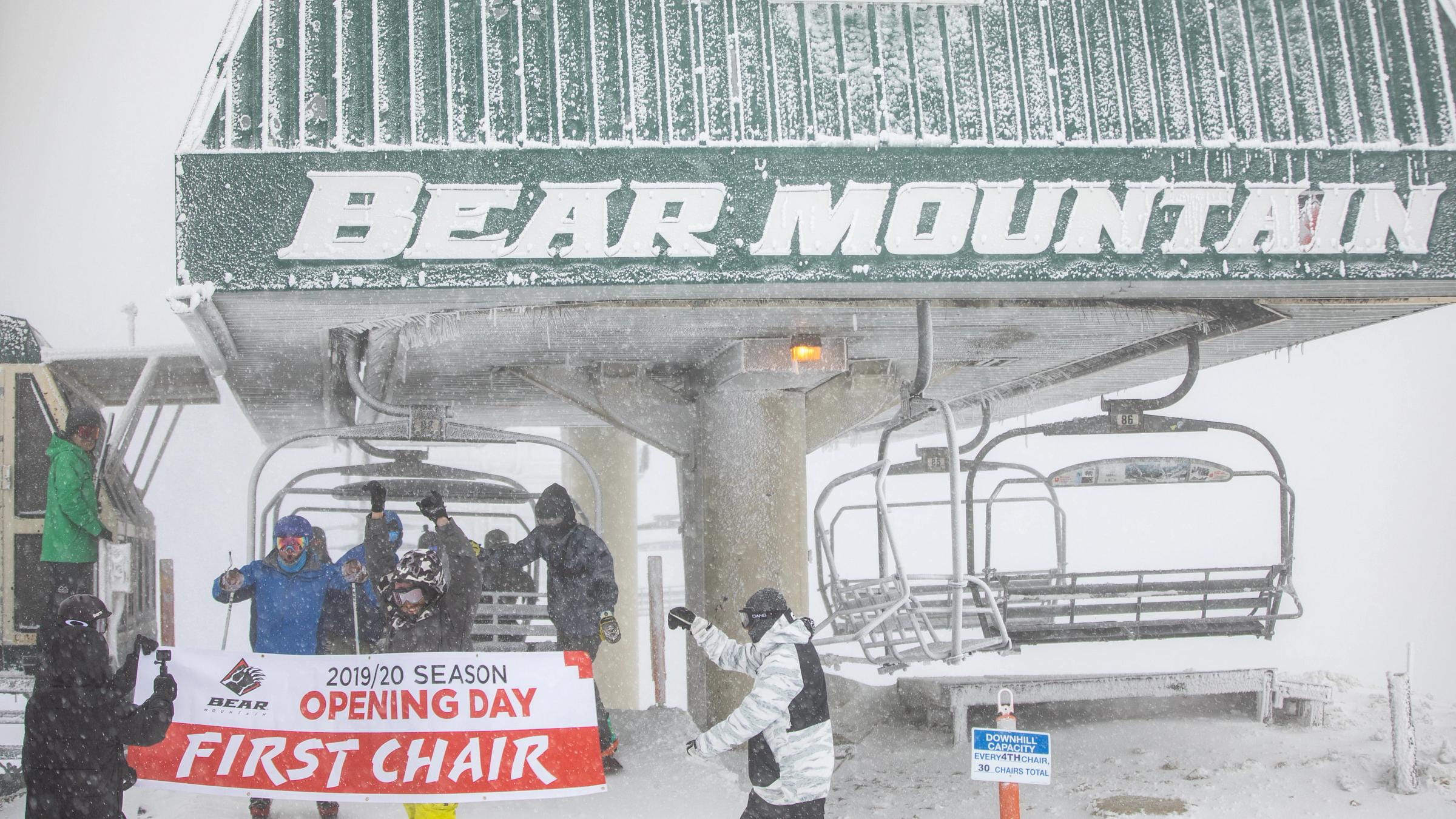Group of people getting off chairlifts with a first chair sign.