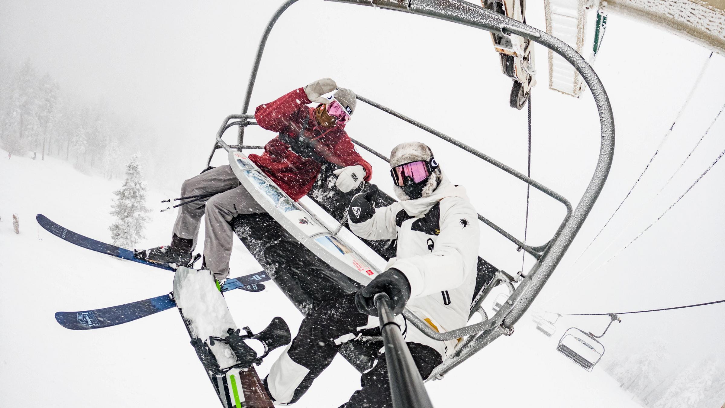 Two friends taking a selfies on a chairlift.