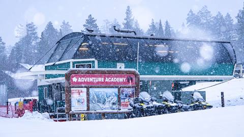 Snow falling at Bear Mountain with a photo of a chairlift and Adventure Academy sign.