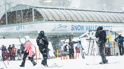 Skiers and snowboarders in the lift line enjoying new snowfall at the base of Snow Valley