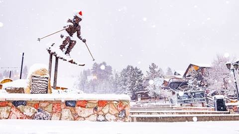 A statue of a skier with a Santa hat on in the base area of Snow Summit during a snow storm with fresh snow.