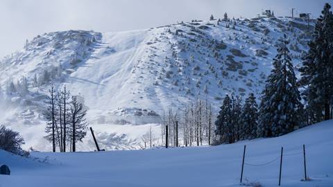 Snow Valley's adorned Slide Peak after a major snowfall and new snow covering the trails, rocks, trees, and bushes.
