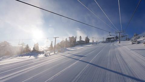 Snow Valley chairlift view looking up to blue skies and sunshine, and down on the freshly groomed corduroy trails.