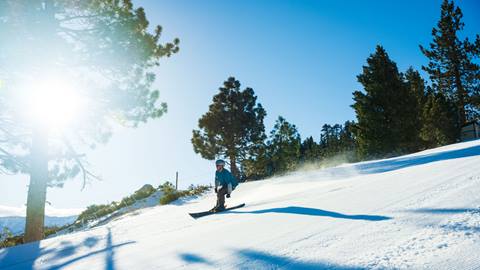 Skier at Snow Valley riding on a groomed trail during a blue sky day