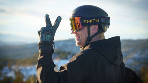 RIder showing the peace sign while smiling in a helmet and goggles