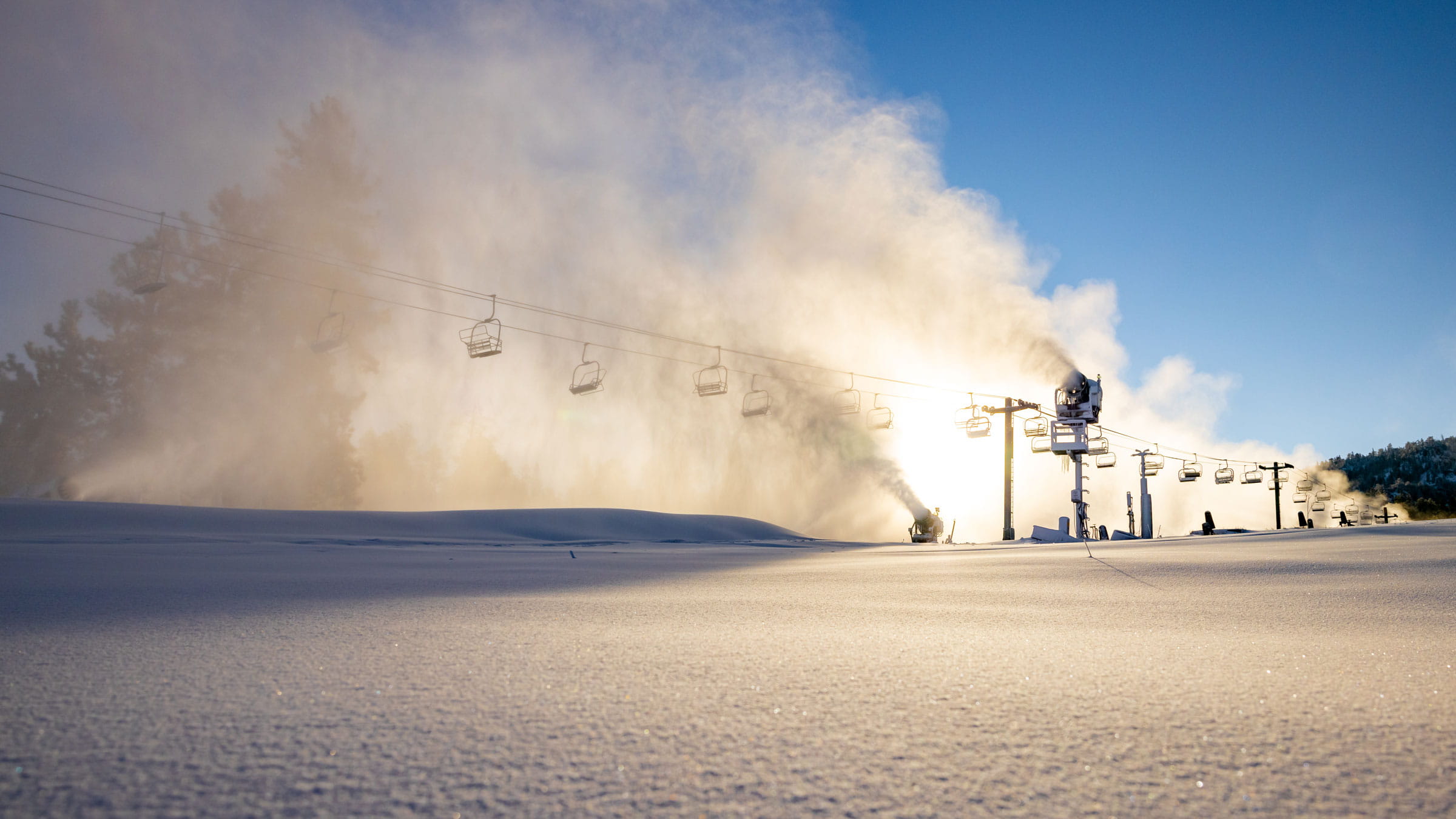 snow guns shooting out snow on a sunny day