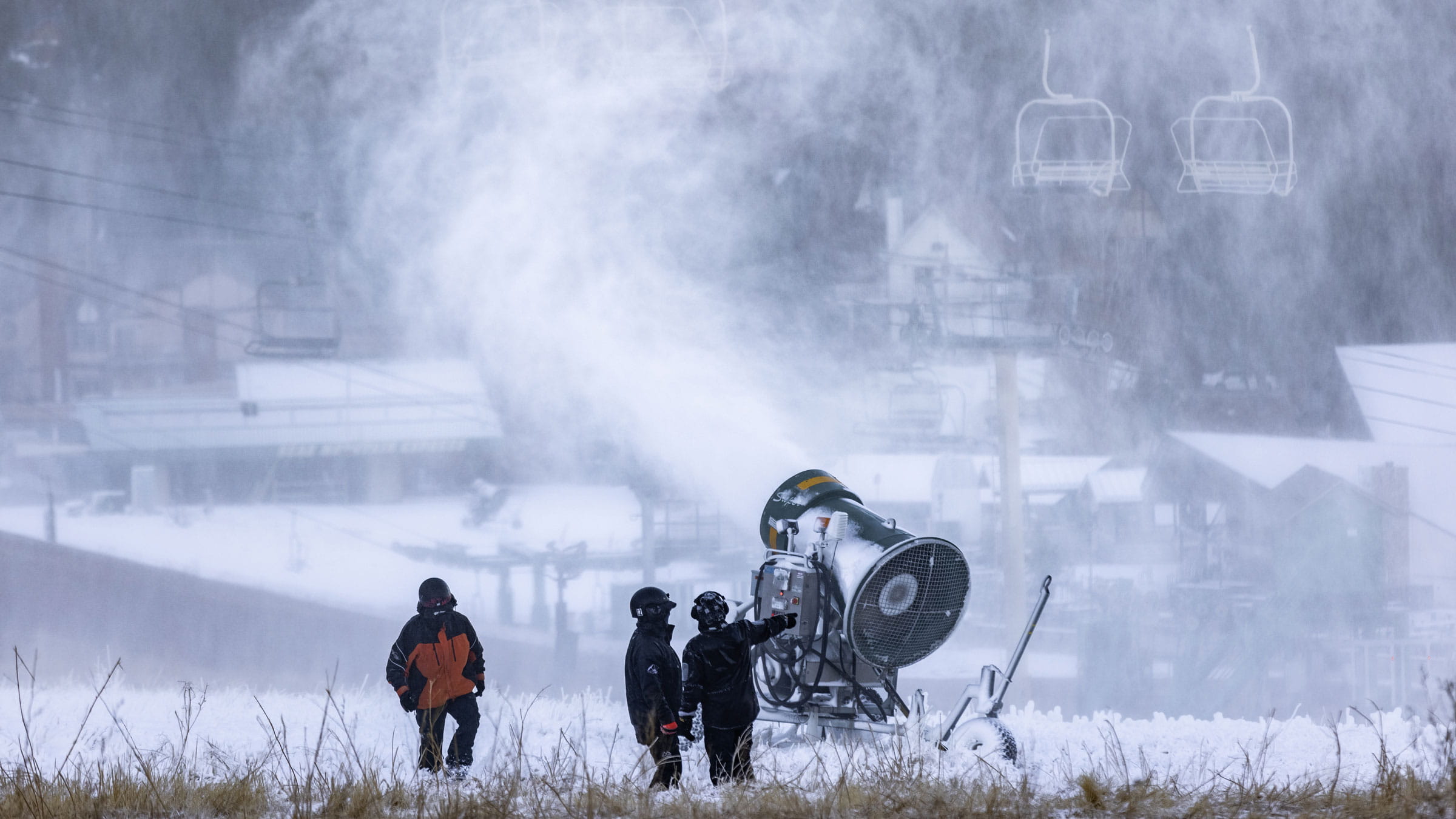 three snowmakers standing next to a snowmaking gun