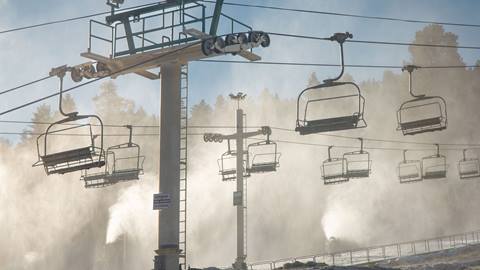 A shot of the chairlift while snowmaking guns blowing.