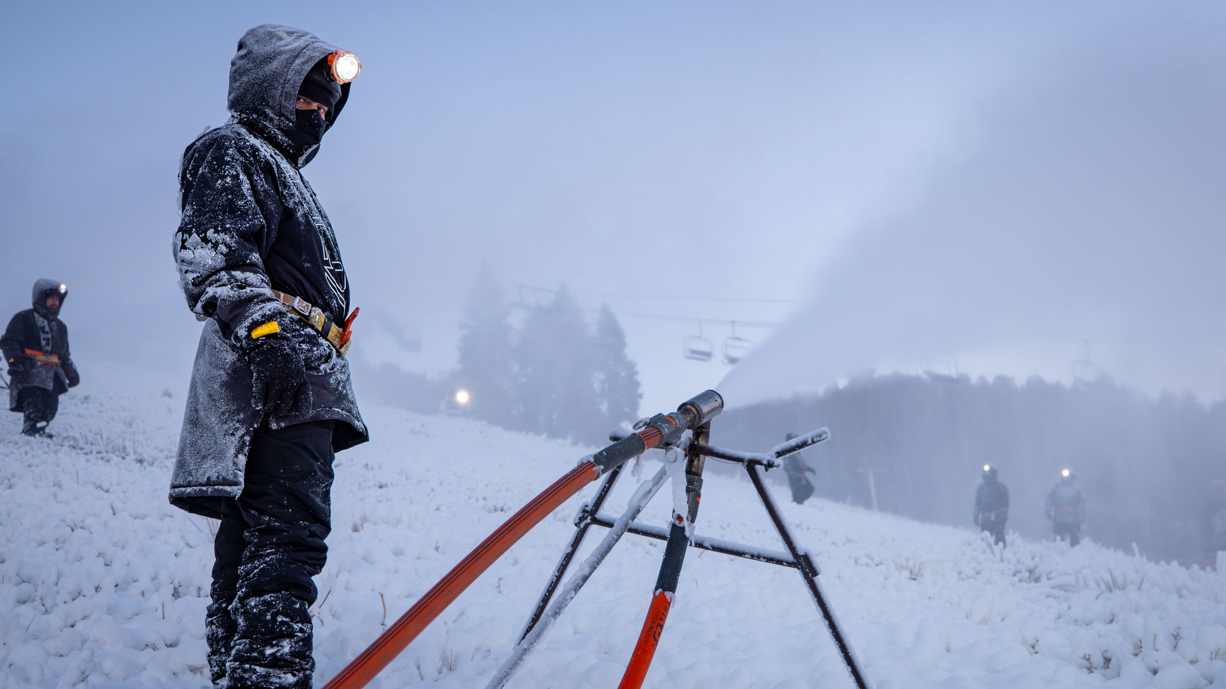 BBMR team member checking snowguns blowing snow onto ski hill.