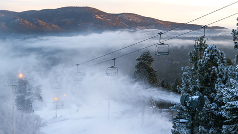 Snowmaking in the early morning at Snow Summit in the winter months with a cloudy mountain in the background