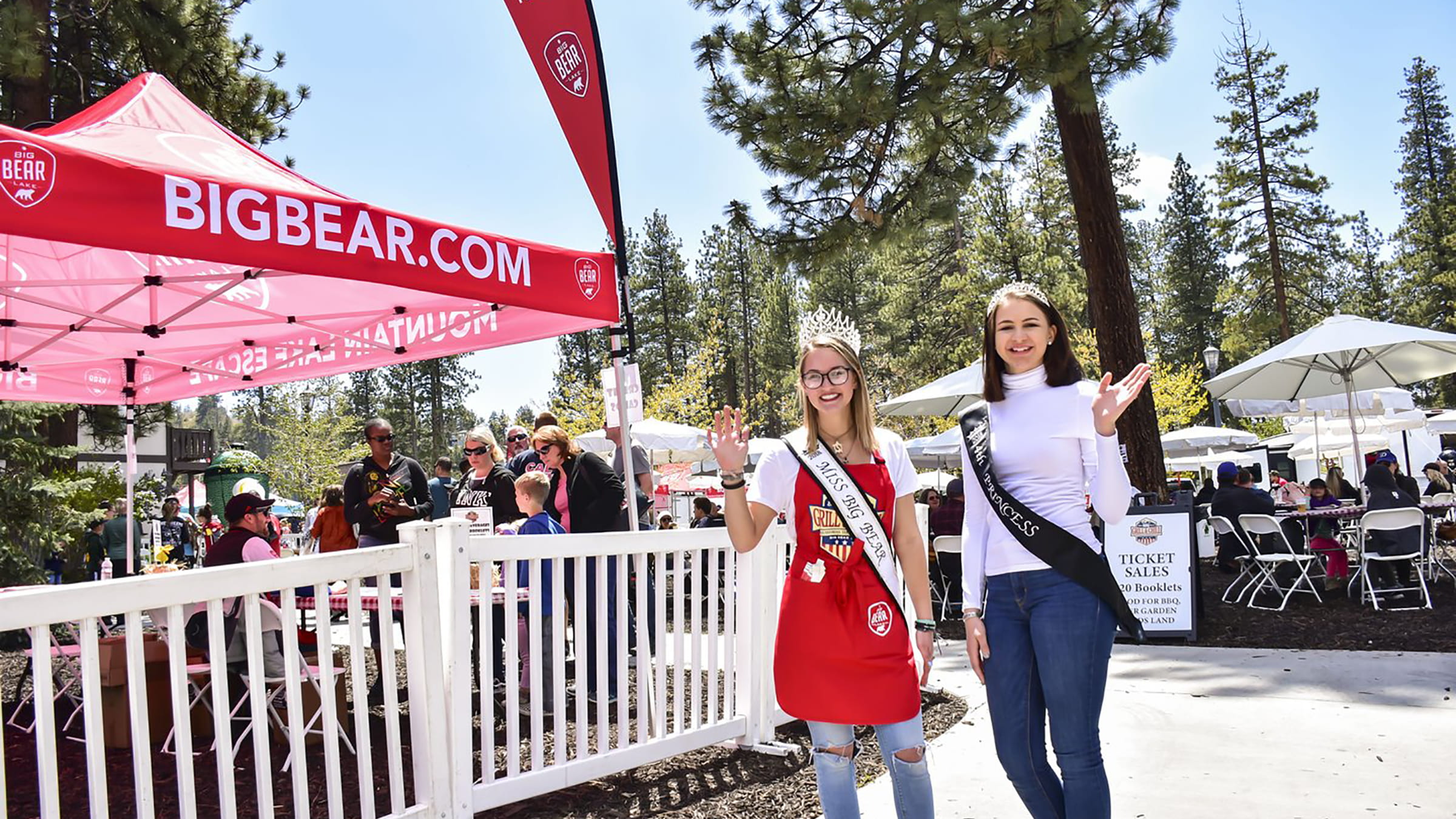 Two females wearing slashed and crowns standing in front of a tent booth at the Grill and Chill BBQ in big bear lake, ca