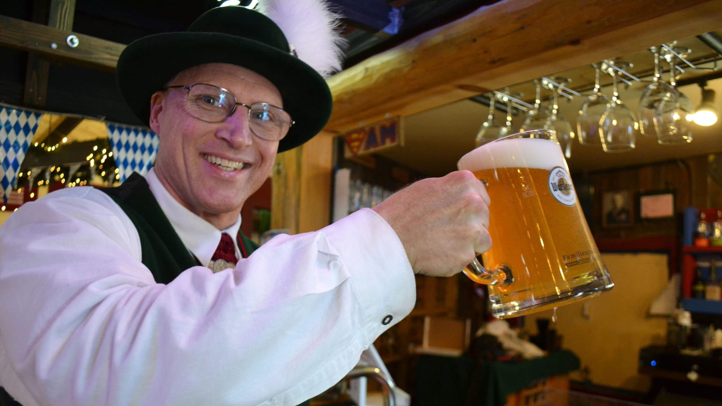 Guy wearing a black hat, holding up a beer stein filled with beer