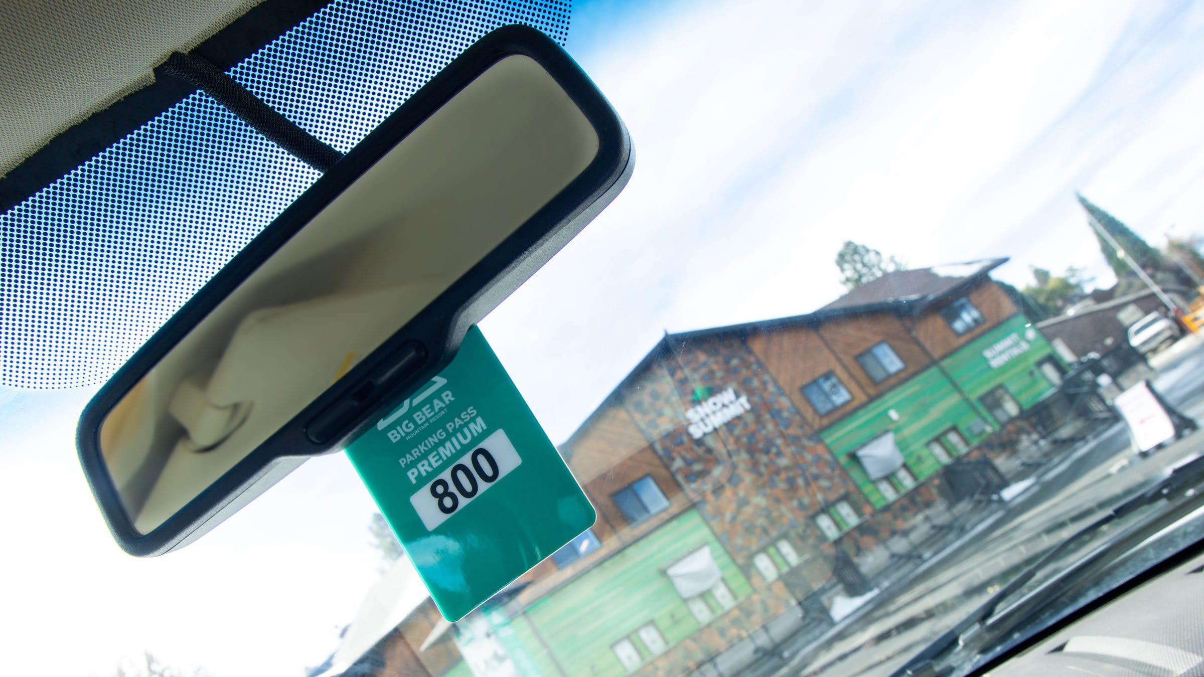 green parking pass hanging from a car, snow summit building in the background