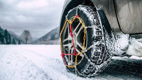 Snow chains on tire. Detail of wheel on wimter road