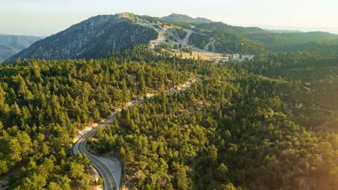 A drone image during the summertime of highway 330 and Snow Valley in the background with forest views surrounding.