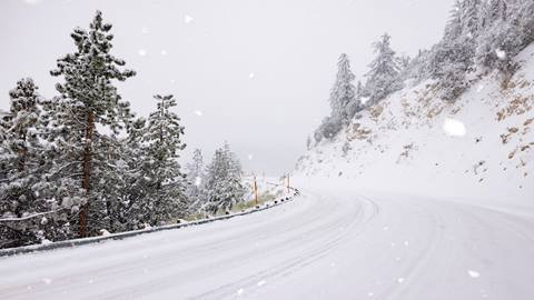 A mountain highway being covered with a blanket of white snow during a winter snowstorm.