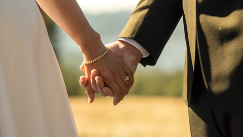 Couple holding hands while the female is wearing an engagement ring