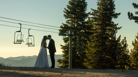 Bride and groom kidding with two chairlifts in the background at the top of snow summit