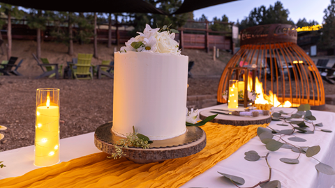 Wedding cake on a table in front of a fire pit in the evening at snow summit