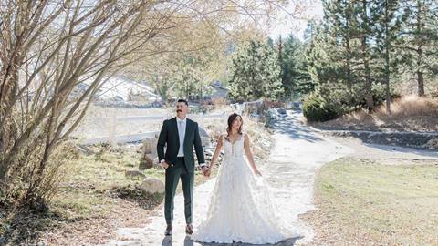 A newlywed couple dressed in their suit and wedding gown on a concrete pathway at Bear Mountain Golf Course.
