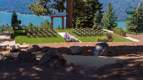 Pristine summer wedding venue, with an alter and chairs, at the top of Snow Summit with alpine views of green forest pine trees and the blue waters of Big Bear Lake in the distance.