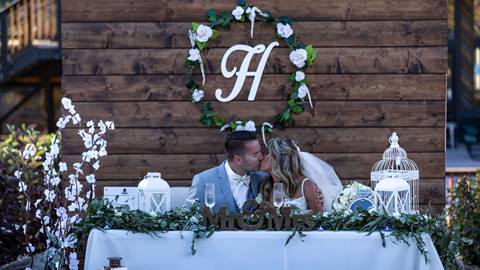 Bride and groom sitting at their reception table kissing